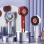 Tres cepillos eléctricos masajeadores capilares en tonos gris, rojo y blanco, con cabezales de cerdas y luz roja, exhibidos sobre pedestales metálicos.