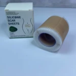 Rollo de cinta de silicona para cicatrizar de 4cm por 1.5m junto a su caja blanca con explicativo sobre su aplicación en zonas quirúrgicas.