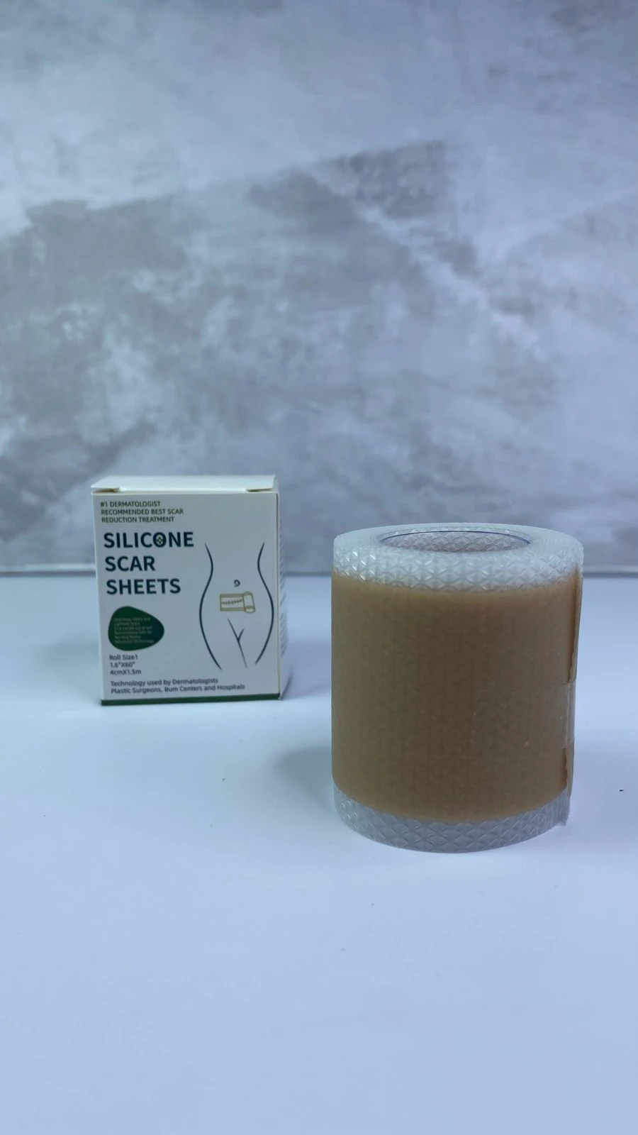 Cinta de silicona para cicatrices en rollo color piel junto a su caja informativa que indica medidas de 4 cm por 1.5 m para tratamiento dermatológico.
