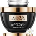 Crema facial Venzen Niacinamide Advanced Hydrating negra con tapa dorada, pétalos blancos.