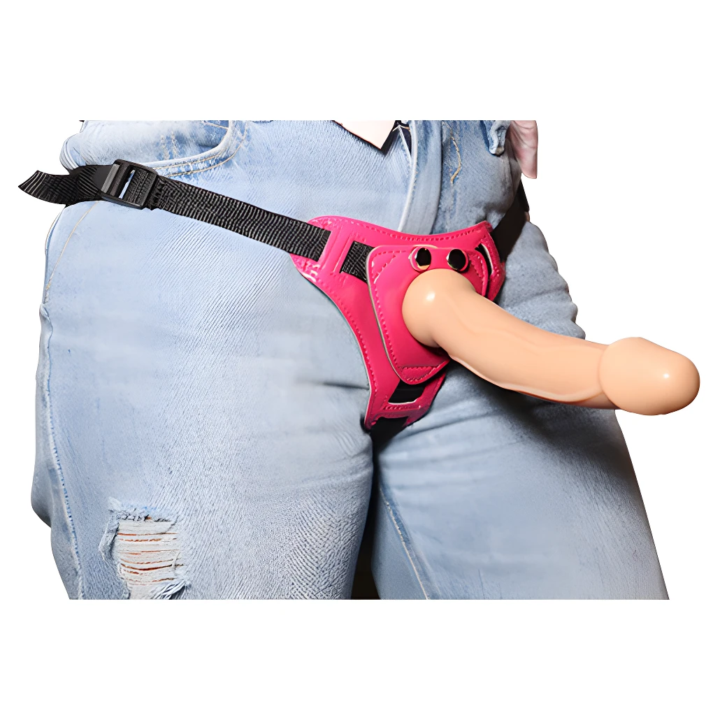 Arnés erótico rosa ajustable con falo de silicona, sobre jeans rasgados.
