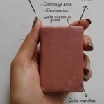 Barra exfoliante Epoch de barro marino en mano, reduce manchas, opacidad y grasa en rostro, axilas, codos y rodillas.