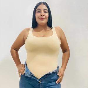 Body de compresión beige con escote cuadrado, usado con jeans azules desabrochados.