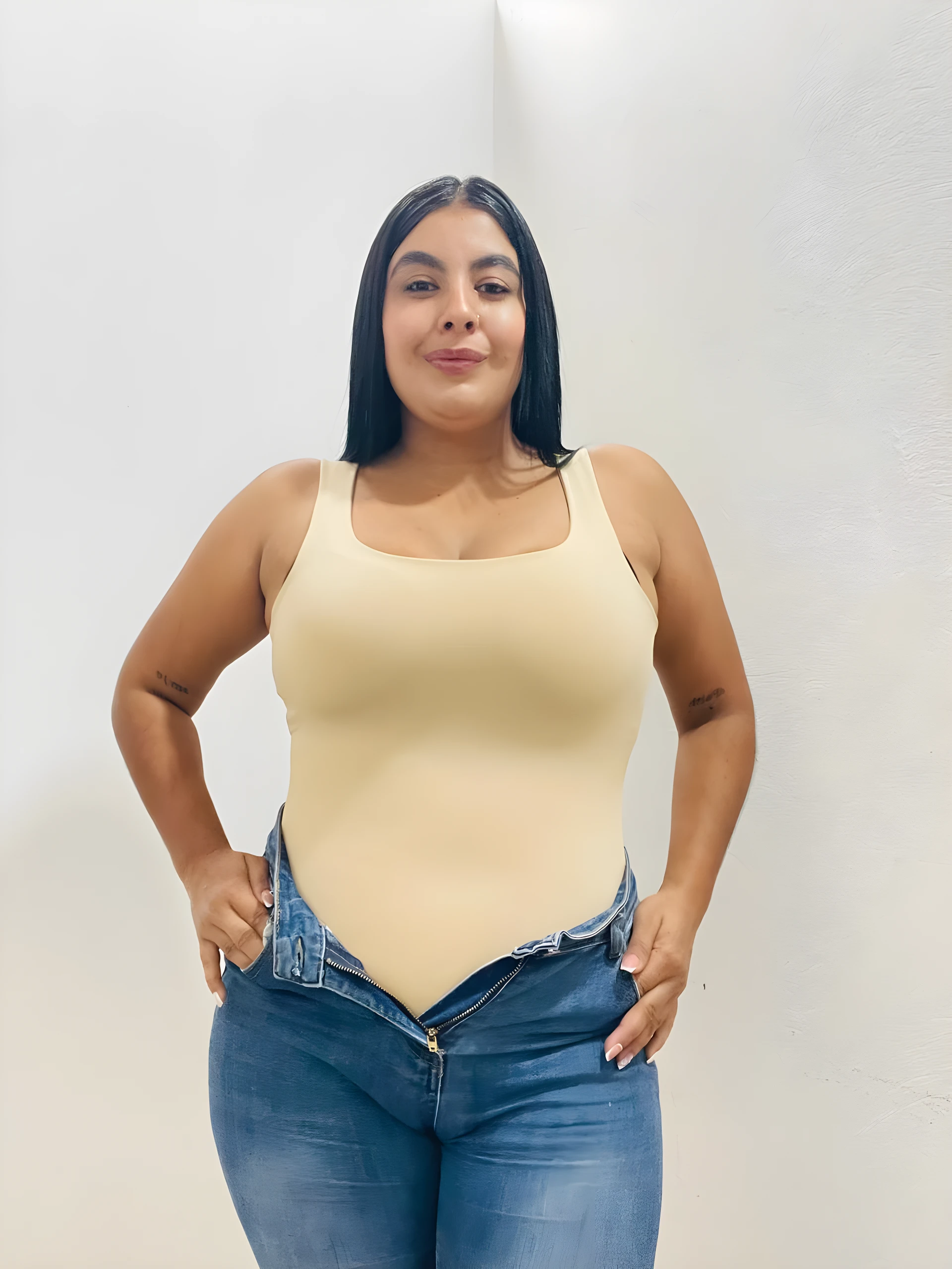 Body de compresión beige con escote cuadrado, usado con jeans azules desabrochados.