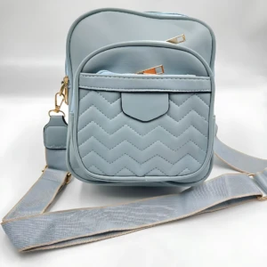 Bolso manos libres azul pastel acolchado con dos compartimentos y correa ajustable.