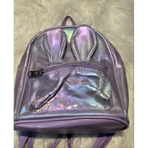 Bolso infantil metalizado morado con orejas de conejo y bolsillo transparente con confeti.