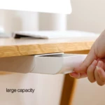 Cajón adhesivo blanco bajo escritorio para organizar objetos, mano inserta en él.