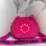 Carriel fucsia de corduroy Bimba y Lola, con logo circular y correa negra estampada.