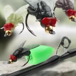 Cebo mosca realista verde y blanco con anzuelo visible, usado en caña de pescar.