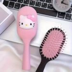 Set de dos cepillos para cabello con diseño de Hello Kitty, uno rosado con relieve de la cara y otro con base negra y cerdas flexibles, sobre un teclado.