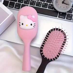 Set de dos cepillos para cabello con diseño de Hello Kitty, uno rosado con relieve de la cara y otro con base negra y cerdas flexibles, sobre un teclado.