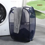 Cesta plegable de malla azul marino para ropa sucia, junto a lavadora, con toalla gris y adorno de panda.