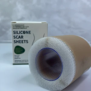 Rollo de cinta de silicona para cicatrices visibles, caja de "SILICONE SCAR SHEETS" al fondo, fondo gris texturizado.