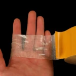 Cinta doble faz transparente en mano con vendas, ideal para pegar objetos delicados.