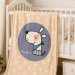 Cobija para bebé color beige con estrellas blancas y diseño de perro animado, dentro de cuna.