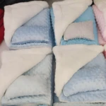 Cobija térmica azul con peluche blanco, almohada gris incluida, ideal para bebé.
