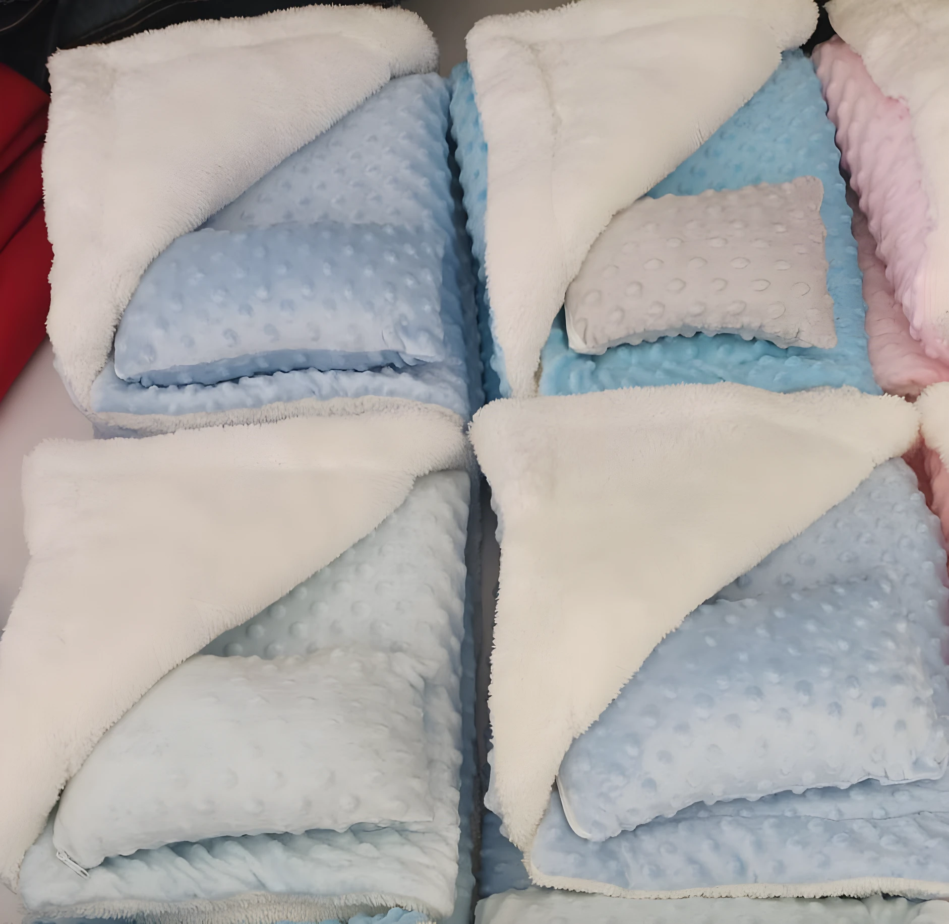 Cobija térmica azul con peluche blanco, almohada gris incluida, ideal para bebé.