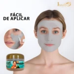 Mujer con mascarilla facial gris, aplicador y frasco del producto.