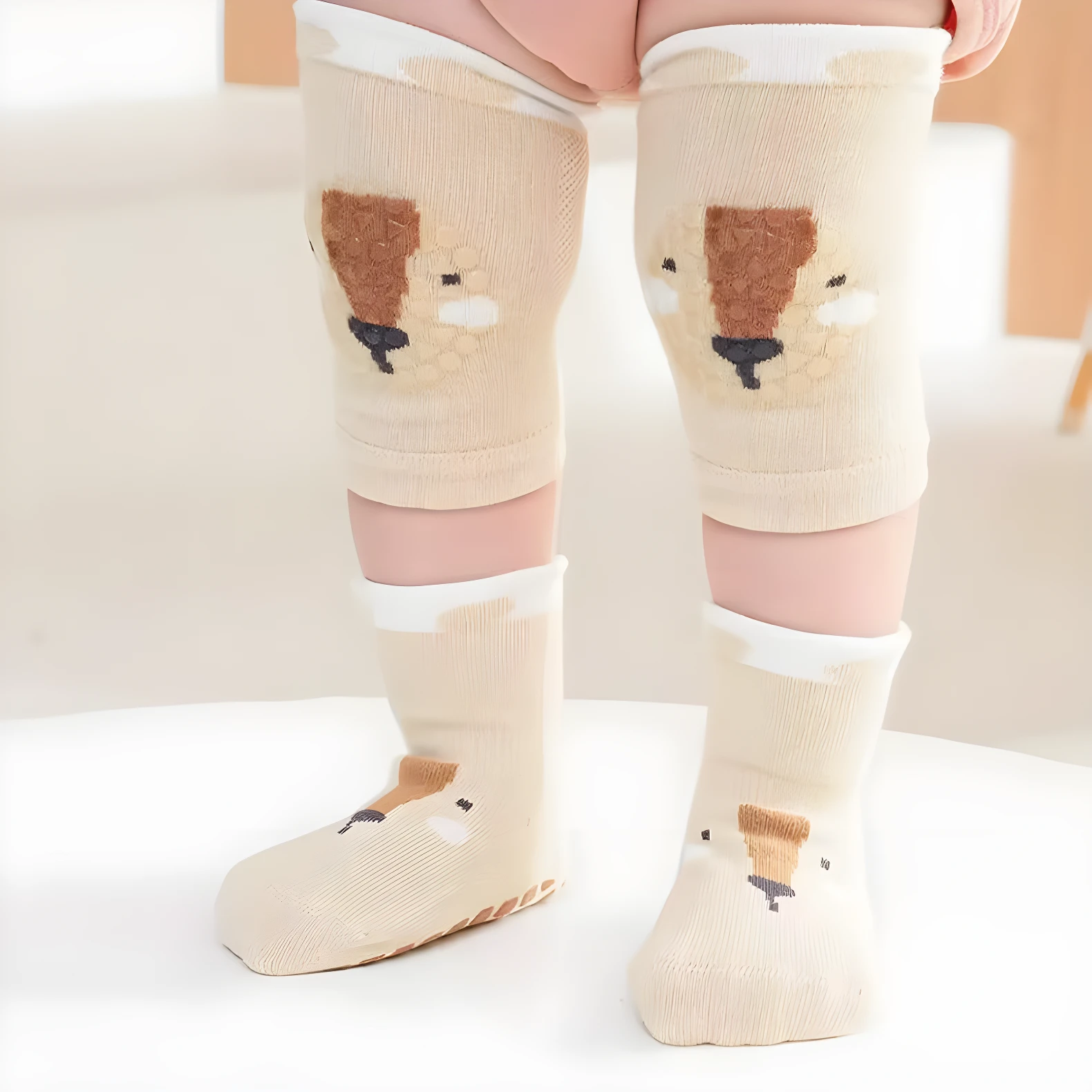Medias y rodilleras antideslizantes beige para bebé con diseño de oso.