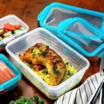 Contenedores para comida con pollo y arroz en uno, ensalada en otro y zanahorias.