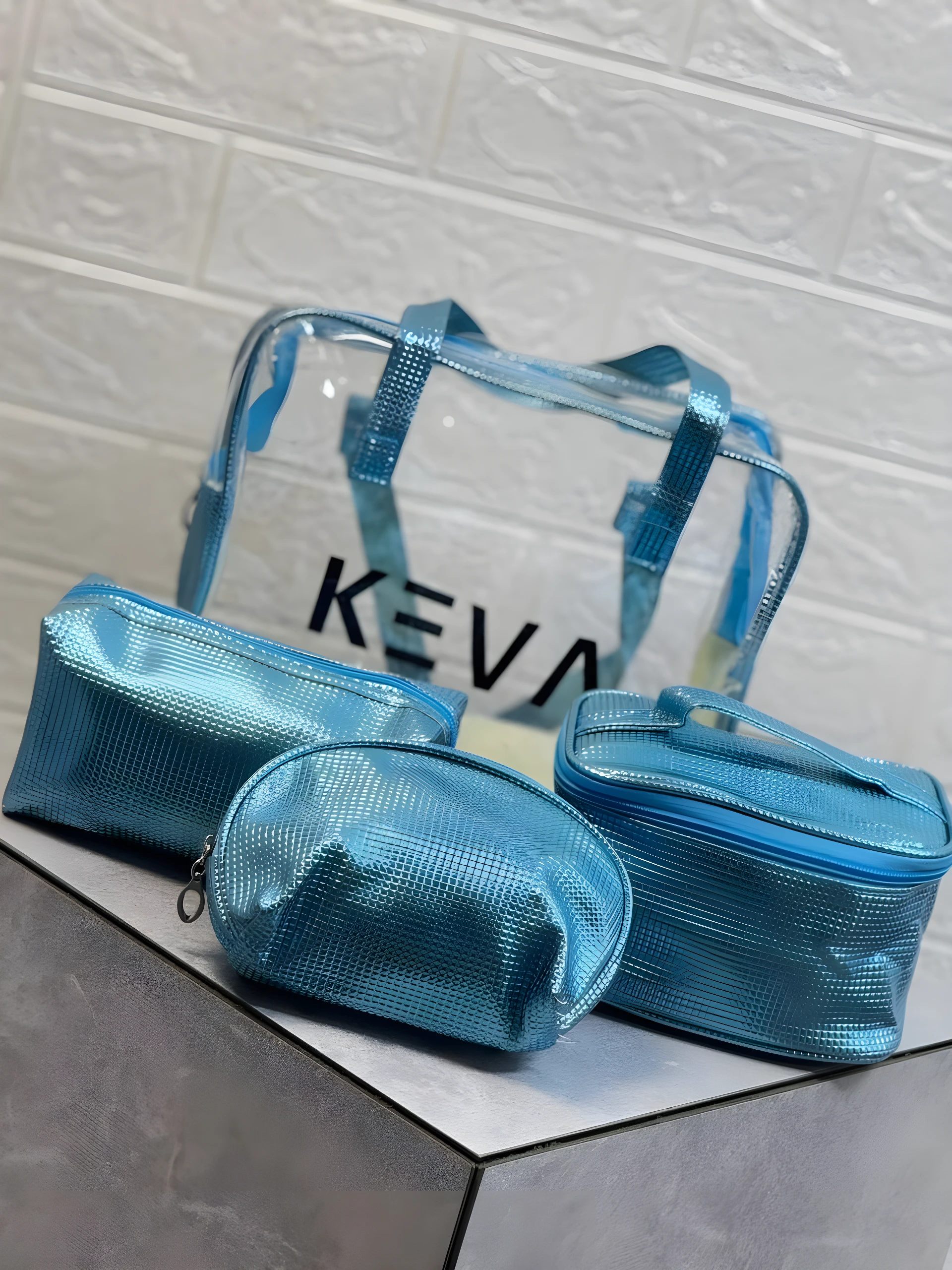 Set de 4 cosmetiqueras brillantes azules con textura, una transparente grande y tres pequeñas, perfectas para organizar.