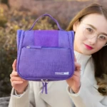 Cosmetiquera colgante morada de viaje con logo "TRAVEL", ideal para organizar artículos de aseo personal.