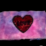Cosmetiquera de peluche difuminado en tonos morado y rosa con corazón de lentejuelas reversibles.