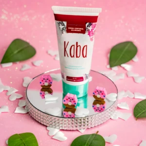 Crema corporal aclarante Kaba 60ml con ositos rosados decorativos sobre espejo, fondo rosa con pétalos.