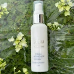 Crema hidratante Xulu Skin Care en envase blanco con detalles plateados, sobre fondo verde y flores, 60 ml.
