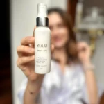 Crema hidratante Xulu Skin Care en envase blanco de 60 ml, sostenida por una mano frente a persona difuminada.
