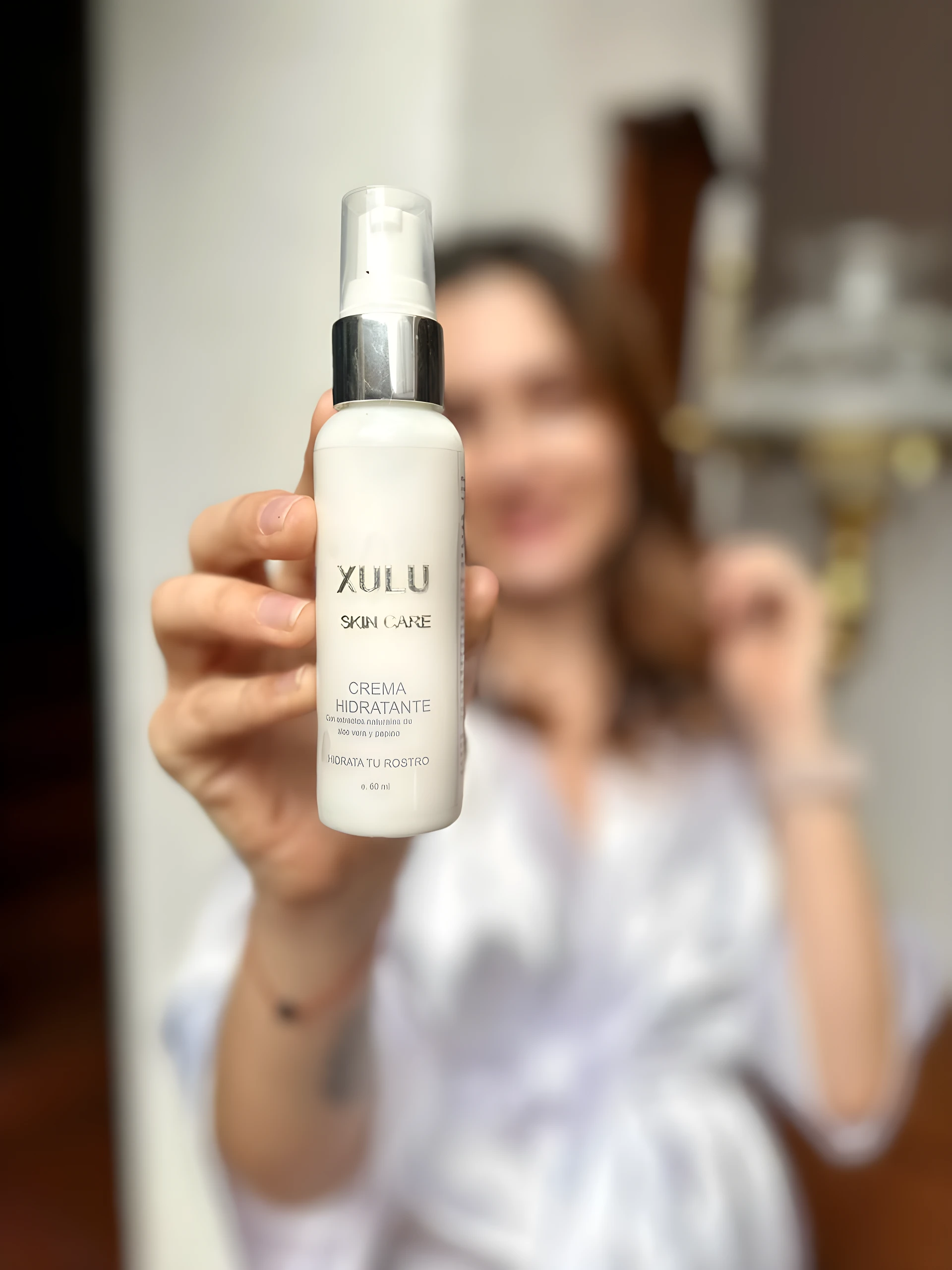 Crema hidratante Xulu Skin Care en envase blanco de 60 ml, sostenida por una mano frente a persona difuminada.