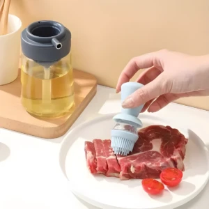 Dispensador de aceite con brocha de silicona azul, rociando carne cruda en plato blanco, con botellas de aceite al fondo.