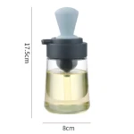 Dispensador de aceite de vidrio transparente con brocha celeste y gris. Mide 17.5cm de alto x 8cm de ancho.