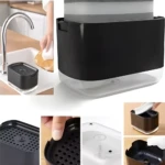 Dispensador de jabón 2 en 1 negro con esponja gris sobre fregadero. Incluye compartimento inferior y rejilla.