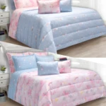 Edredón infantil doble faz con diseño de unicornios y arcoíris en tonos pastel, sobre camas vestidas.