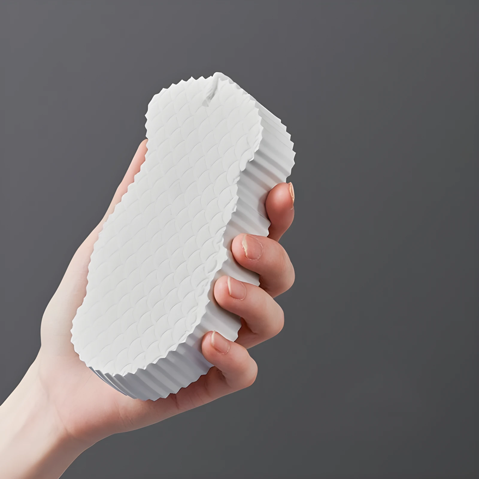 Esponja exfoliante 3D blanca con textura de escamas, sostenida en mano.