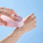 Esponja exfoliante mágica 3D rosa en uso, eliminando piel muerta en brazo.