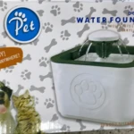 Fuente de agua para perros y gatos, blanca con borde verde, con dibujo de huellas y huesos, y texto "Pet".