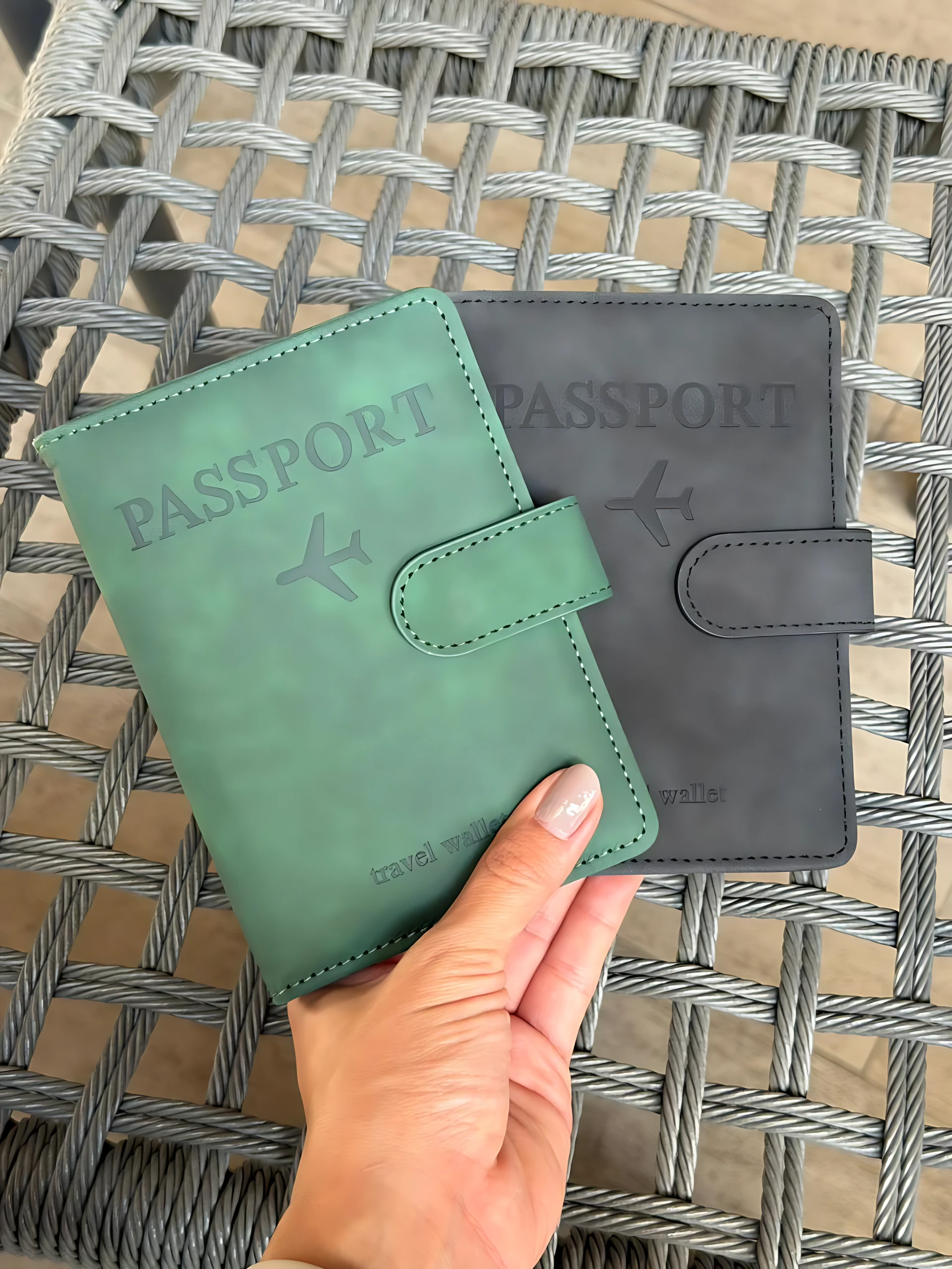Set x2 fundas de viaje para documentos, verde y gris, con avión grabado, sobre mesa tejida.