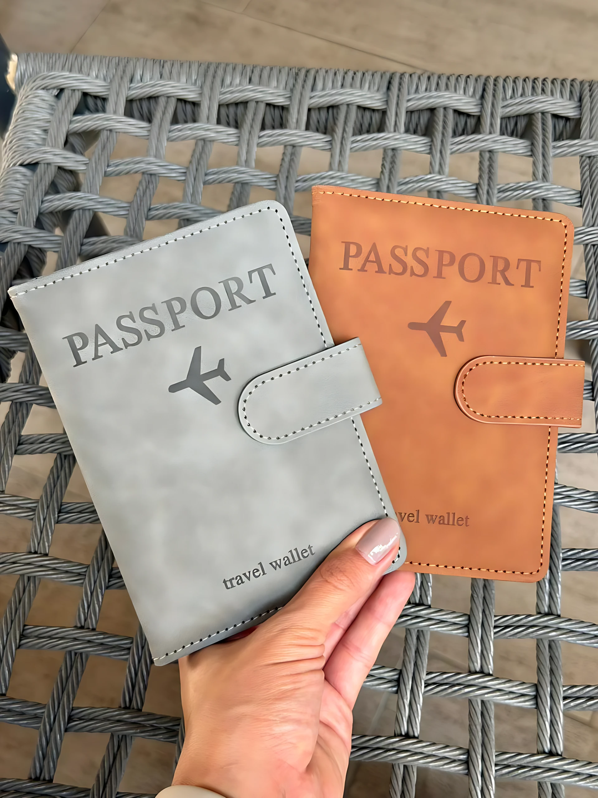 Dos fundas de pasaporte, una gris y otra naranja, con diseño de avión y texto "travel wallet".