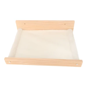 Hamaca de pared para gato en madera clara con superficie de felpa blanca y ventana panorámica.