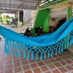 Hamaca colgante azul con flecos, ideal para relajar niños, vista exterior con terraza y escaleras.