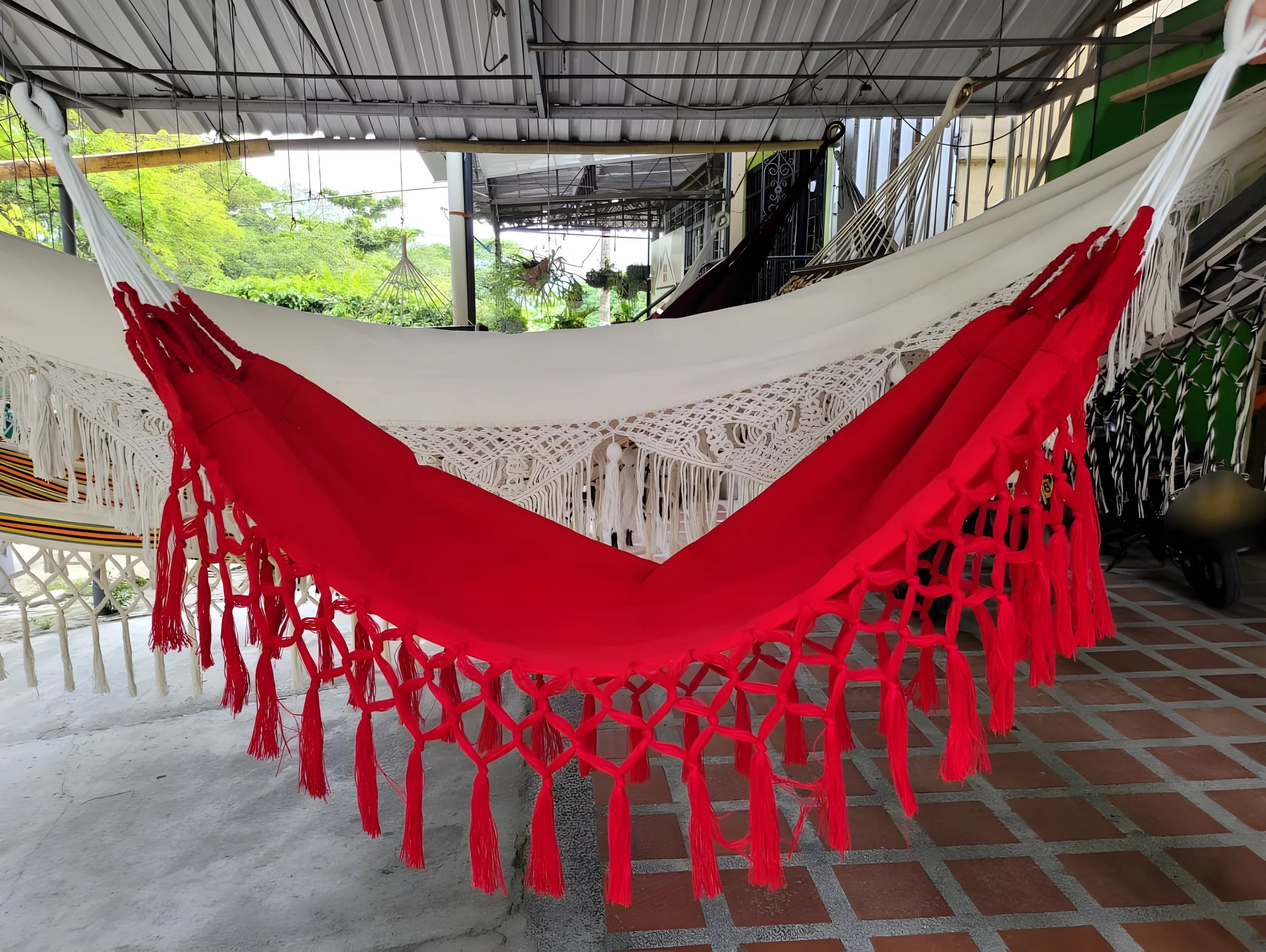 Hamaca infantil roja y blanca con flecos, ideal para relajación segura al aire libre.