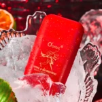 Inhalador O'Cheal rojo con menta, cubierto de gotas de agua y hielo, fondo rojo borroso.