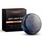 Jabón antigray de Lorenge Exclusive, esfera azul oscuro con textura granulada, junto a su empaque negro que indica reducción de canas y ingredientes naturales como bambú y ginseng.