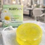 Jabón en gel Rubyskin de camomila, transparente y amarillo, con texto grabado, sobre malla blanca.