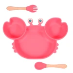 Vajilla adherente rosa para bebé en forma de cangrejo, con tenedor y cuchara de madera.