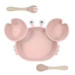 Plato adherente rosado en forma de cangrejo con tenedor y cuchara de madera para bebé.