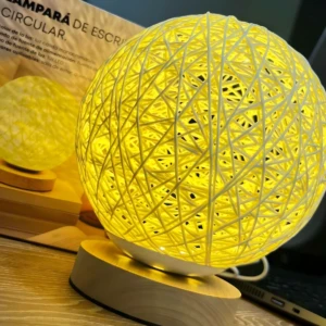 Lámpara circular tejida amarilla con base de madera, luz LED cálida, ideal para escritorio.