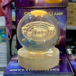 Lámpara de noche esfera cristal 3D sistema solar, base madera, luz cálida, fondo morado galaxia.